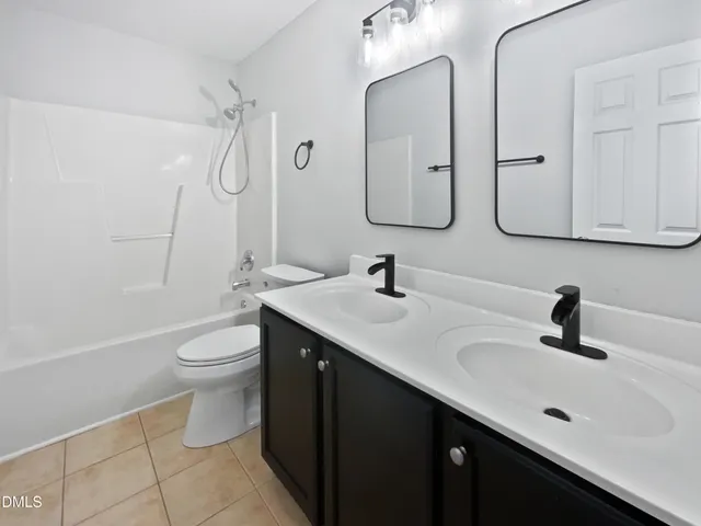 a bathroom with a double vanity sink toilet and mirror