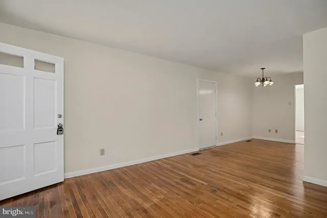 a view of an empty room with wooden floor and a ceiling fan