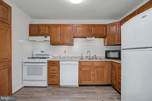 a kitchen with granite countertop wooden cabinets and white appliances
