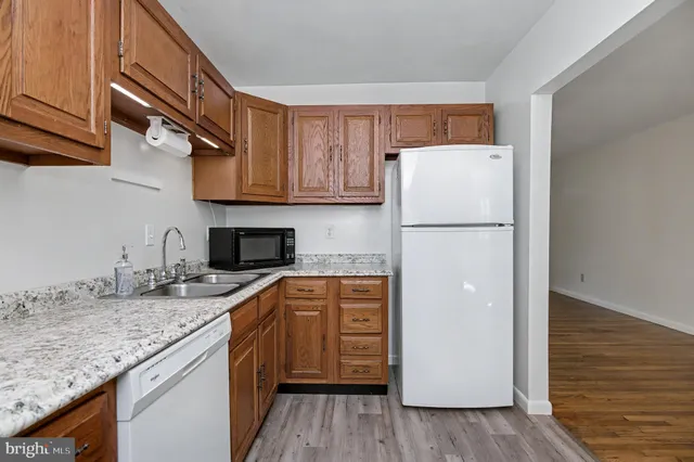 a kitchen with stainless steel appliances granite countertop a sink and cabinets with wooden floor
