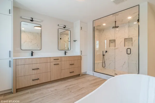 a spacious bathroom with double vanity sinks a shower and a mirror