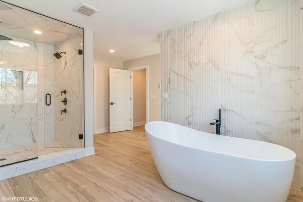 a white bath tub sitting in a bathroom and shower