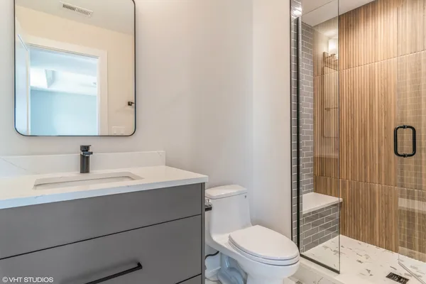 a bathroom with a toilet a sink a mirror a vanity and shower