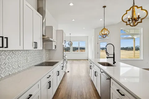 a large white kitchen with wooden floor and a window