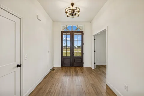 an empty room with wooden floor fireplace and windows