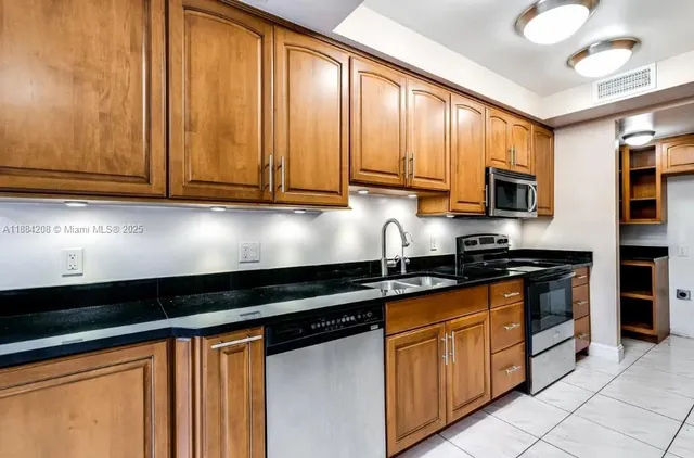 a kitchen with granite countertop stainless steel appliances a sink dishwasher and cabinets with wooden floor