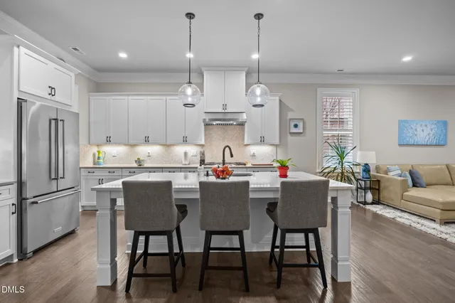 a kitchen with stainless steel appliances granite countertop a dining table chairs refrigerator and sink