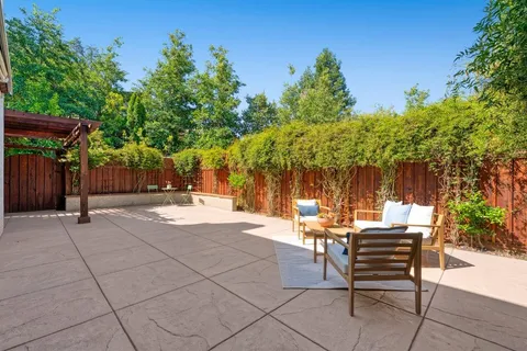 a view of a patio with a table and chairs under an umbrella and a barbeque