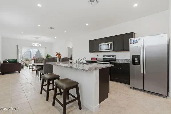 a kitchen with stainless steel appliances granite countertop a sink a stove a microwave a refrigerator and island