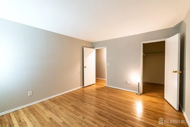 a view of an empty room with wooden floor and closet