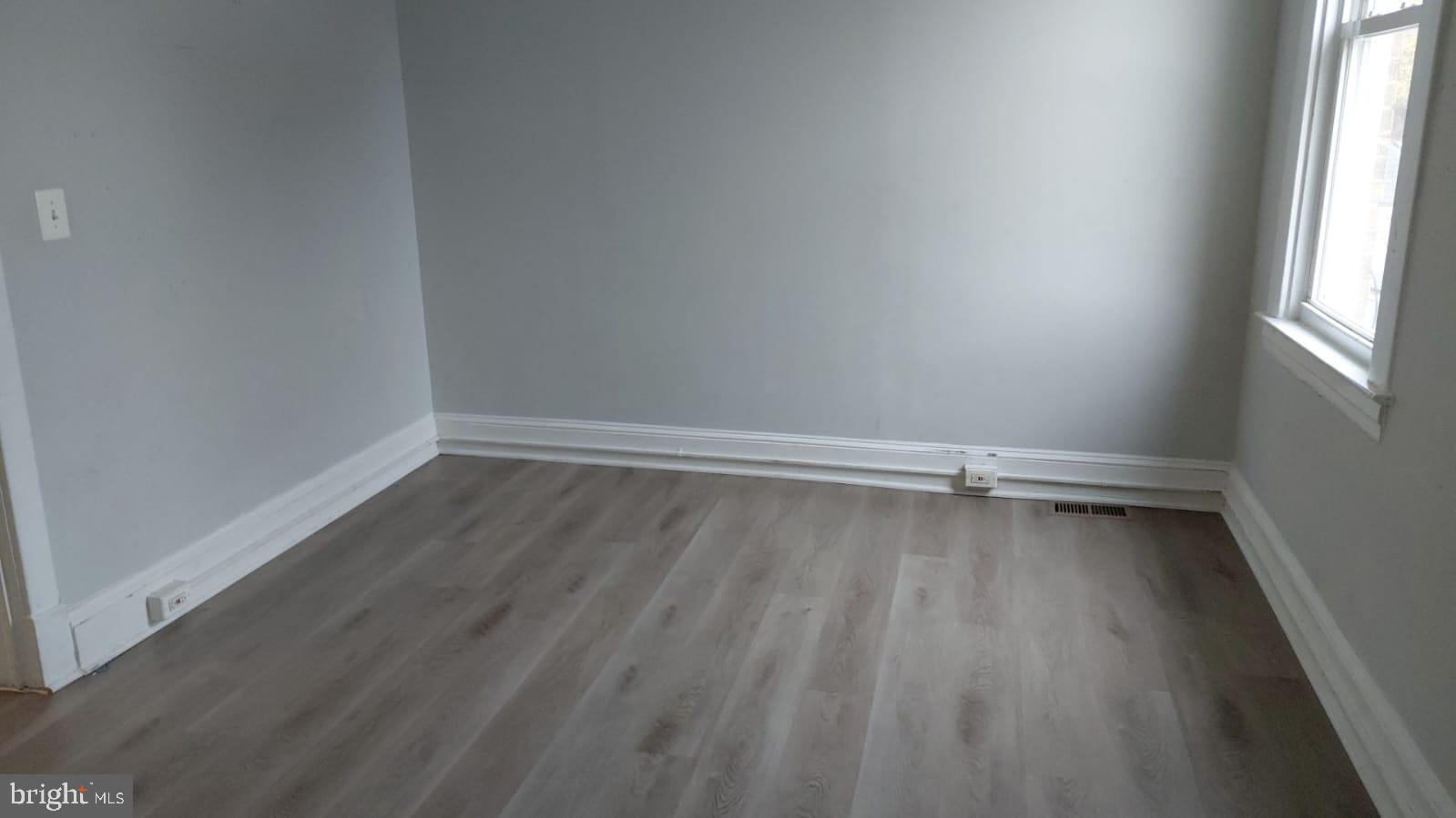 2518 Barclay Street Baltimore, MD 21218 - Photo 2 of 16 a view of an empty room with wooden floor and a window