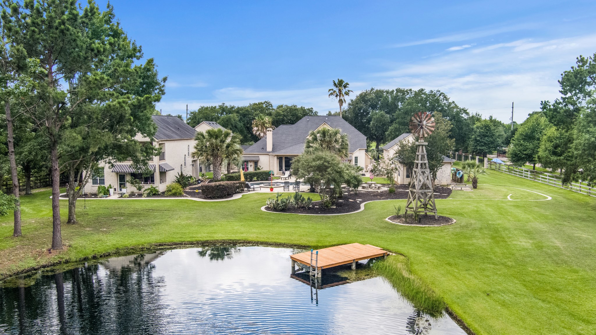 13914 Skinner Road Cypress, TX 77429 - Photo 5 of 50 Peaceful pond with a private dock overlooking the manicured backyard, mature trees, landscaped grounds, and decorative windmill.