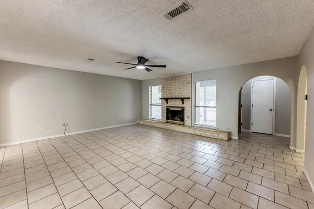 an empty room with windows and fireplace