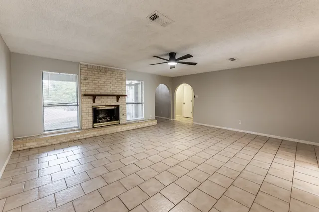 an empty room with windows and fireplace