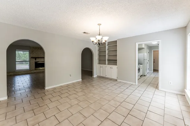 a view of empty room with window and chandelier