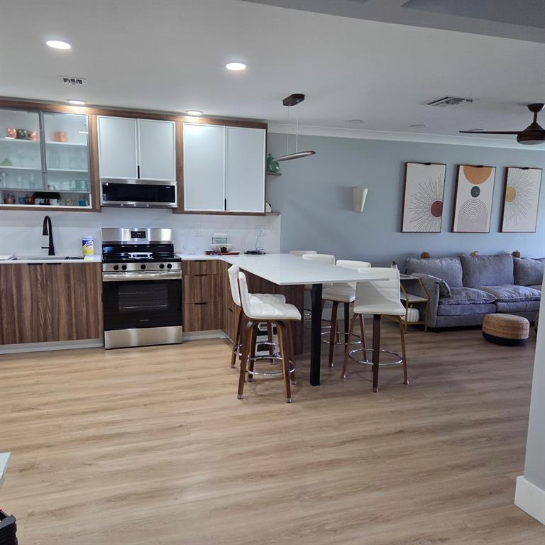 300 Southwest Golfview Terrace, Unit 135 Boynton Beach, FL 33426 - Photo 16 of 25 a kitchen with stainless steel appliances kitchen island granite countertop a stove and a wooden floor