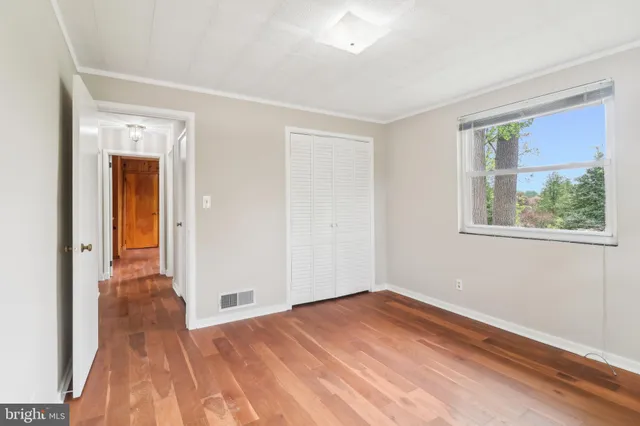 a view of empty room with wooden floor and fan