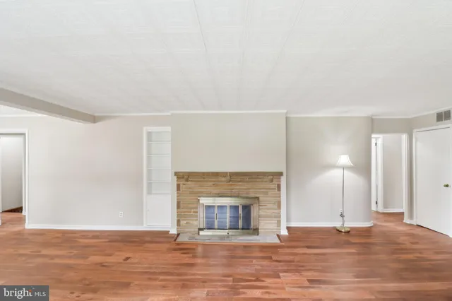 an empty room with wooden floor fireplace and windows