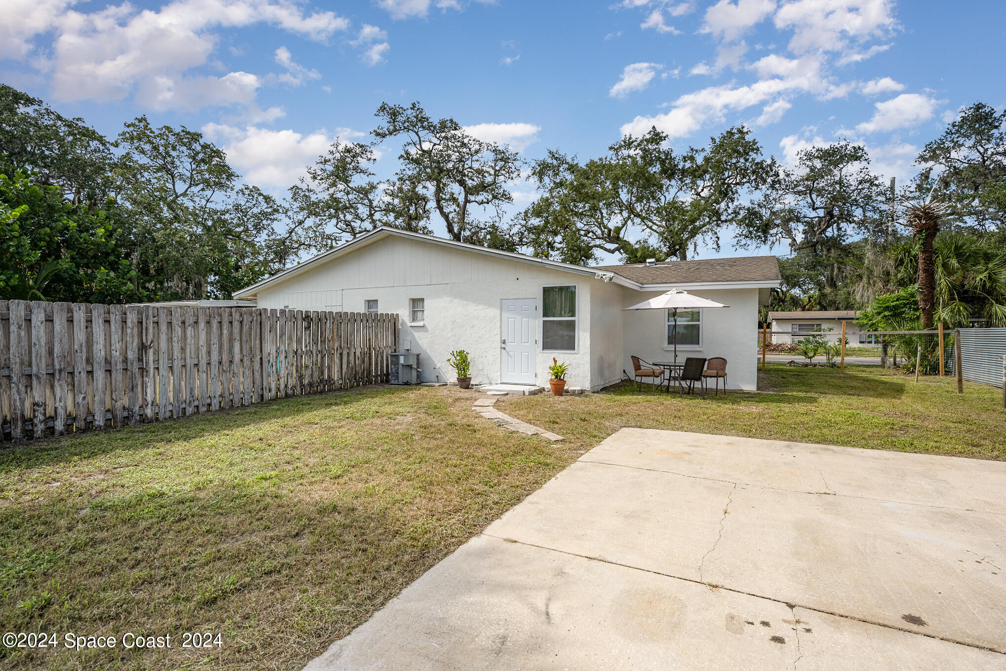 889-881 Sarno Road Melbourne, FL 32935 - Photo 21 of 25 a view of a white house with a yard and large tree