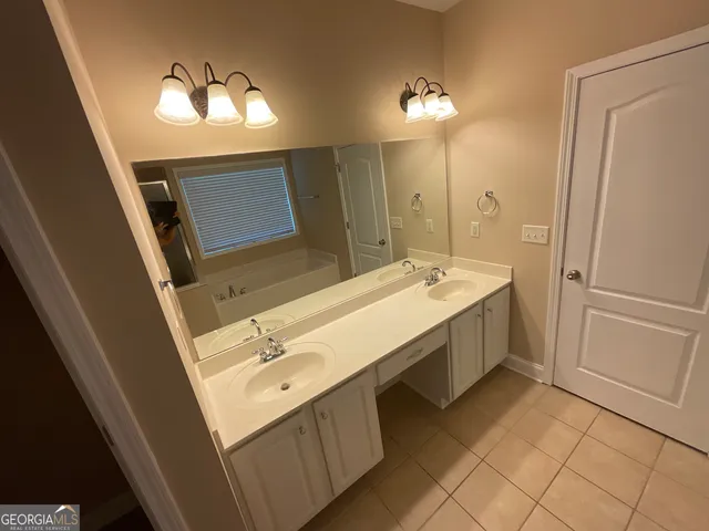 a spacious bathroom with a double vanity sink a mirror and a shower