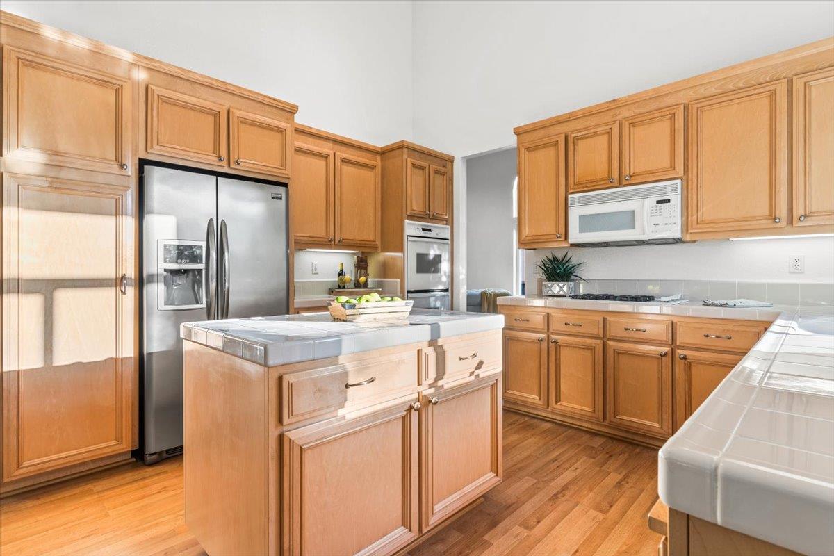 9395 Durango Lane Gilroy, CA 95020 - Photo 11 of 30 a kitchen with stainless steel appliances granite countertop a stove a refrigerator a sink dishwasher and wooden cabinets with wooden floor