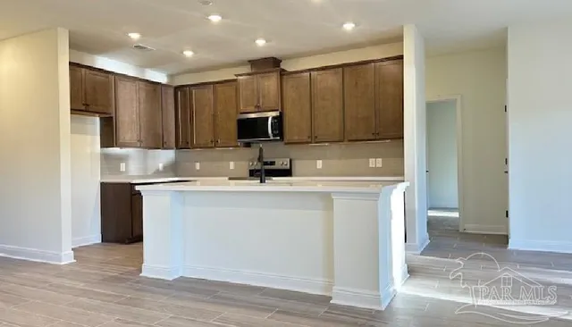 a kitchen with kitchen island a sink stainless steel appliances and cabinets