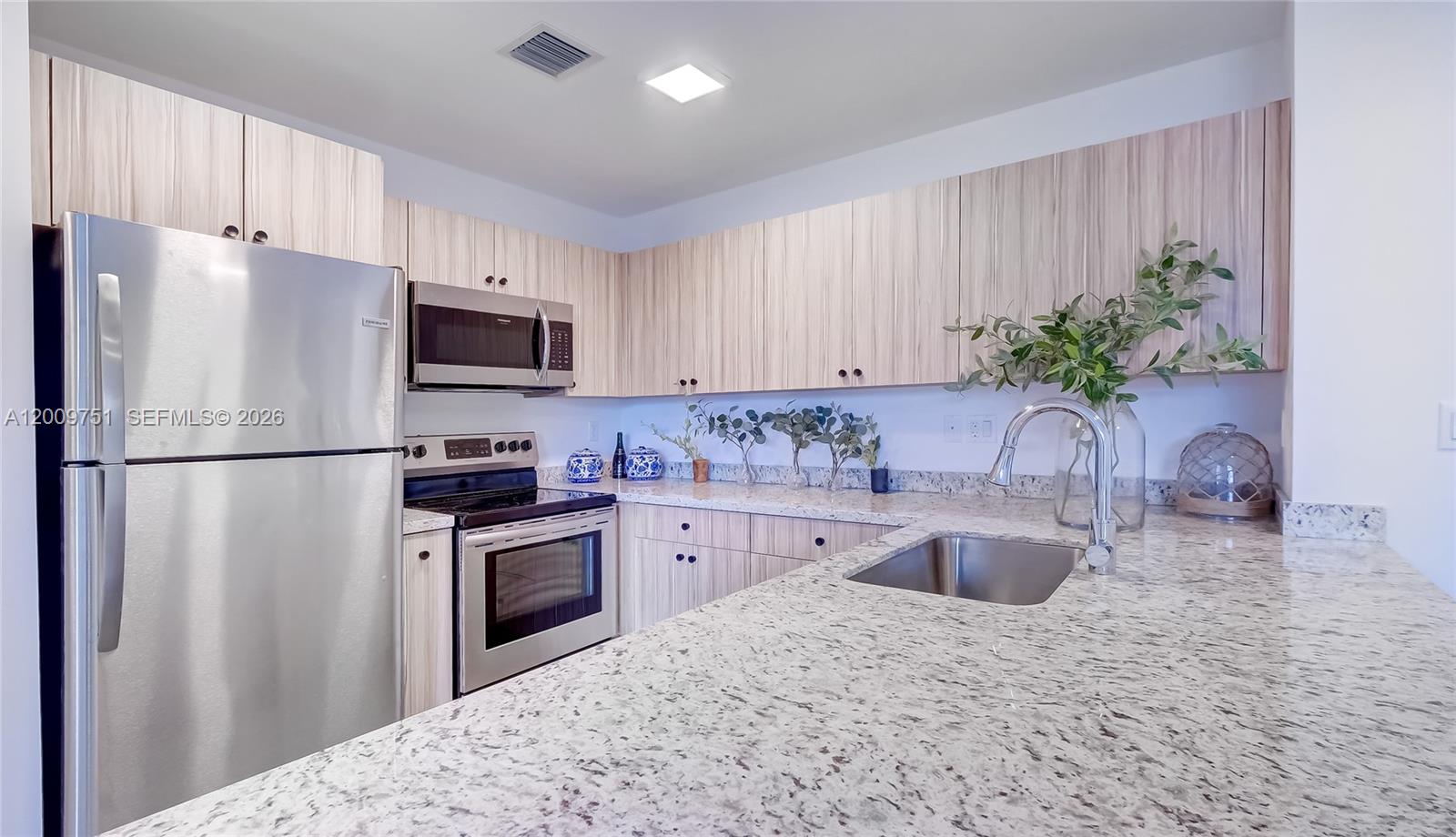 2010 Southwest 25th Terrace, Unit 404 Miami, FL 33133 - Photo 12 of 17 a kitchen with granite countertop a refrigerator sink stove and microwave