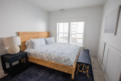 a bedroom with a bed a window and wooden floor