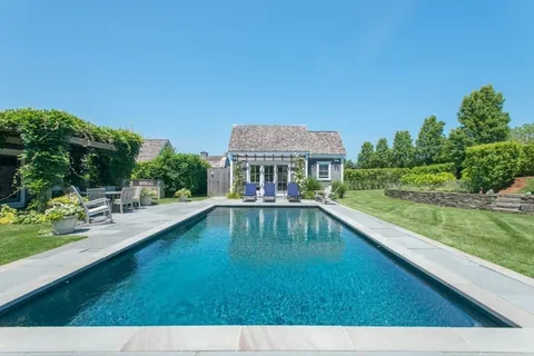 a view of pool with lawn chairs and large trees