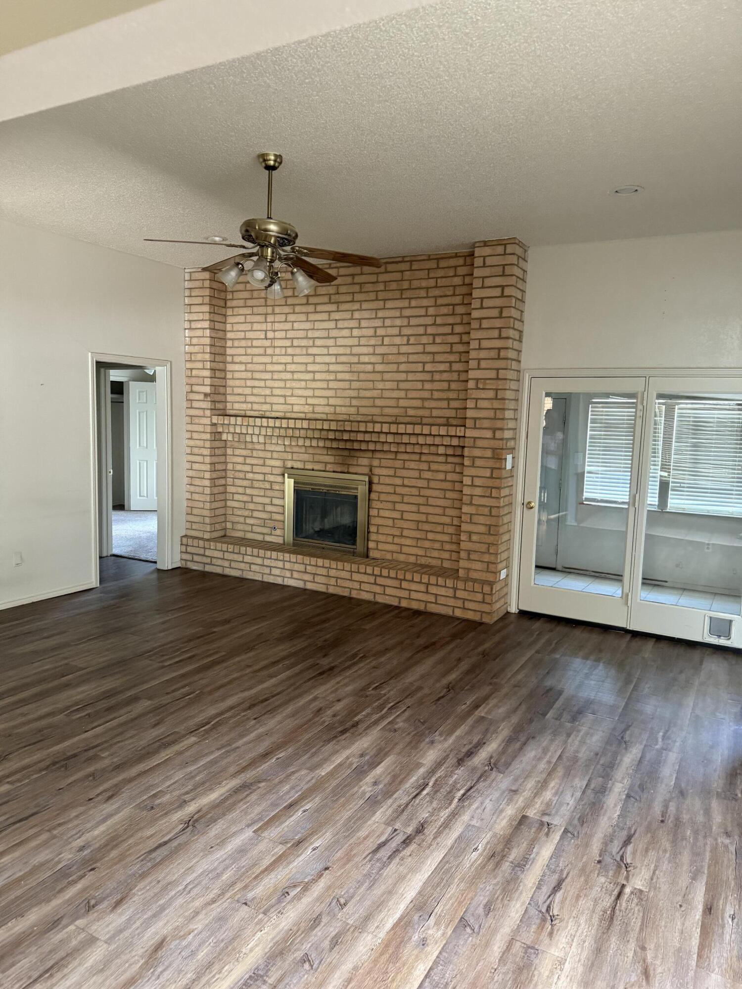 6004 68th Street Lubbock, TX 79424 - Photo 4 of 17 an empty room with wooden floor fireplace and windows