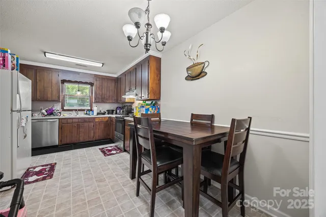 a kitchen with a dining table chairs and refrigerator