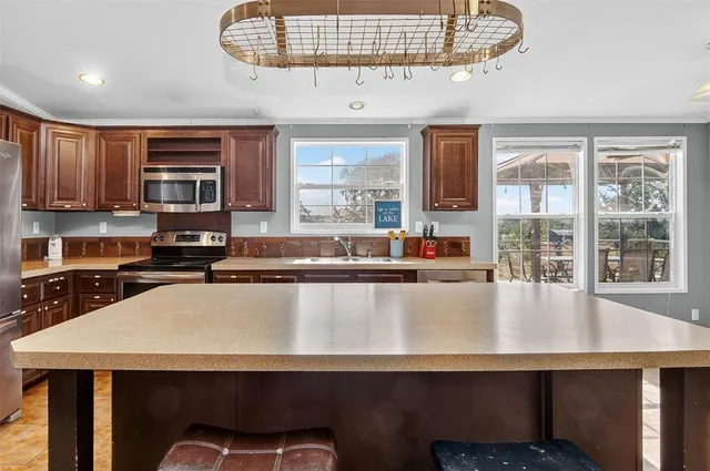 a living room with stainless steel appliances granite countertop a table chairs and a wooden floors
