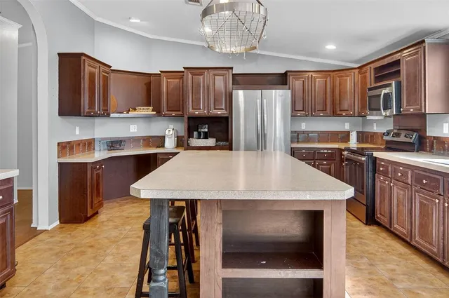 a kitchen with stainless steel appliances kitchen island granite countertop a kitchen island a stove a table and chairs