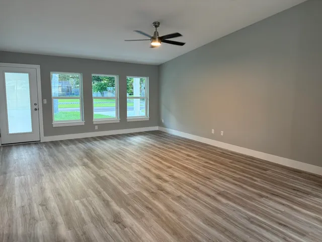 an empty room with wooden floor and windows