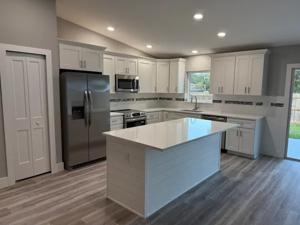 a large kitchen with stainless steel appliances granite countertop a stove a refrigerator and a sink
