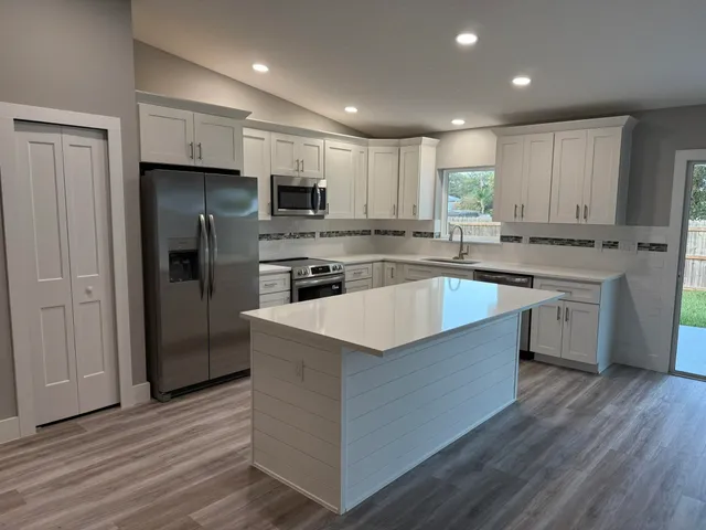 a large kitchen with stainless steel appliances granite countertop a stove a refrigerator and a sink