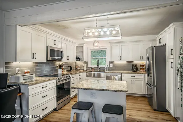 a kitchen with a center island appliances cabinets and a counter top space