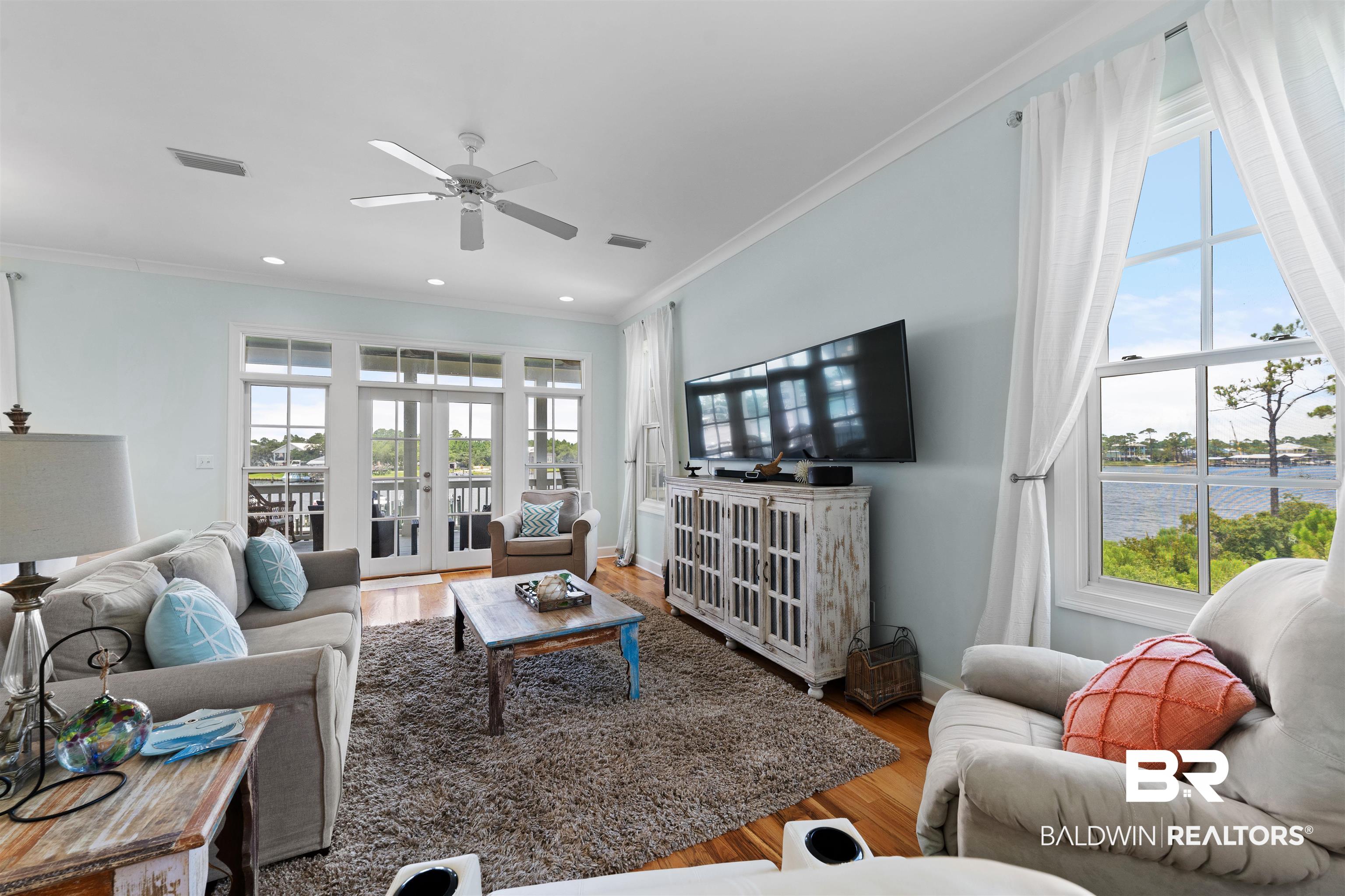 3434 Mariner Circle Orange Beach, AL 36561 - Photo 16 of 38 Living room with a water view, a healthy amount of sunlight, hardwood / wood-style flooring, and french doors