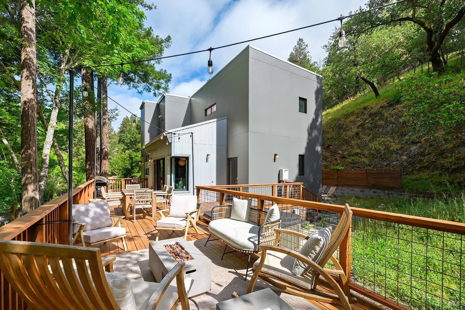 2563 Mill Creek Road Healdsburg, CA 95448 - Photo 2 of 42 a view of a patio with couches chairs under an umbrella with large trees