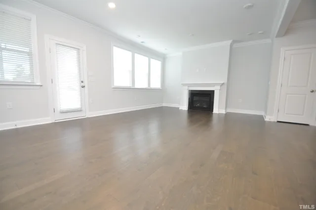 a view of a kitchen and an empty room with wooden floor