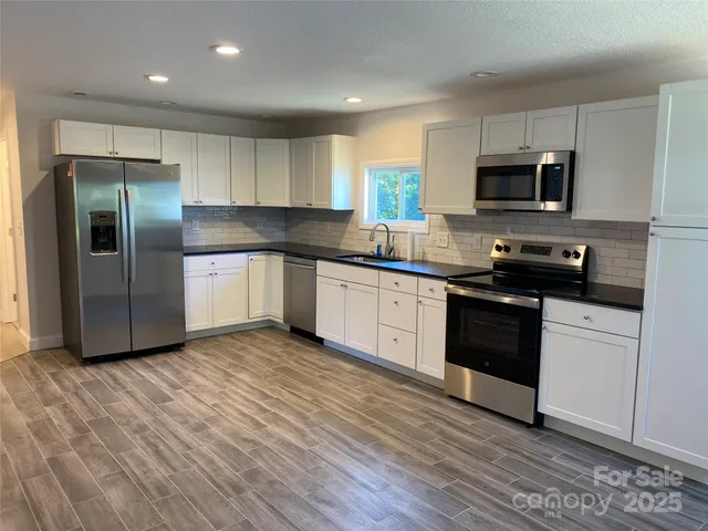 a large kitchen with stainless steel appliances granite countertop a stove a sink and a refrigerator