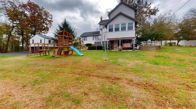 a view of a house with a big yard and large trees