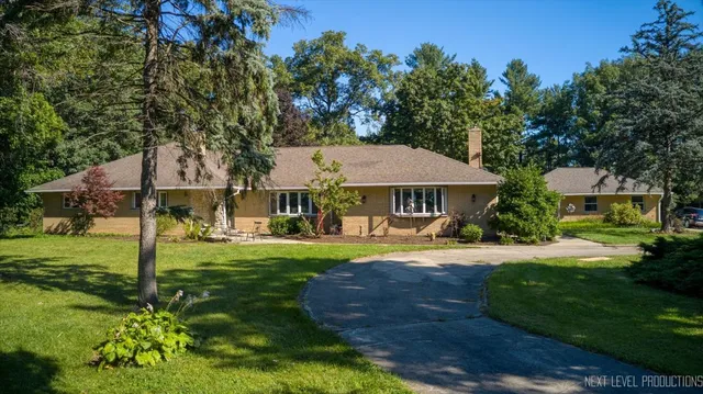 a view of a big house with a big yard and potted plants and large trees