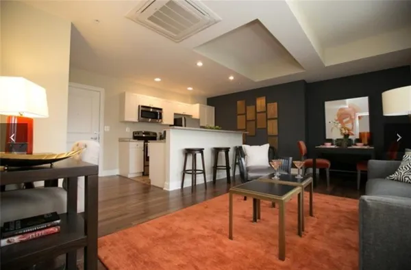 a living room with furniture a wooden floor and a kitchen view