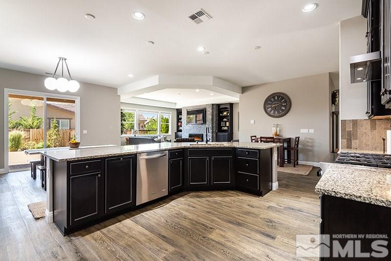 10055 Gold Cup Lane Reno, NV 89521 - Photo 7 of 25 a large kitchen with a stove a sink dishwasher and a fireplace with wooden floor