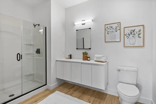 a bathroom with a toilet a sink a shower and mirror