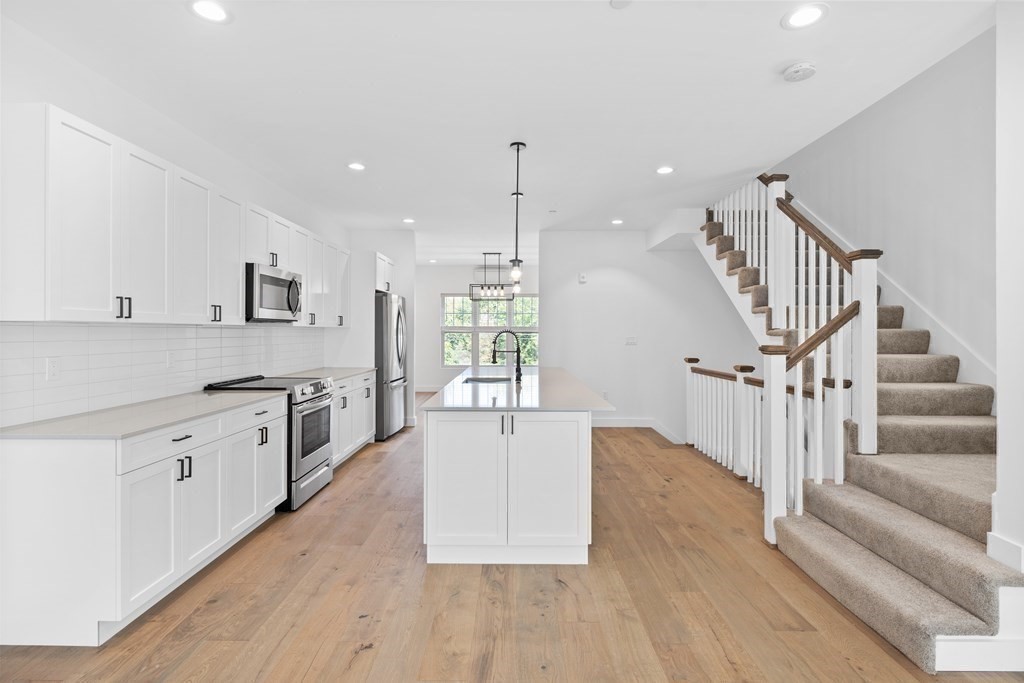 635 Main Street, Unit TH6 Wilmington, MA 01887 - Photo 2 of 29 a kitchen with granite countertop a stove a sink and a wooden floors