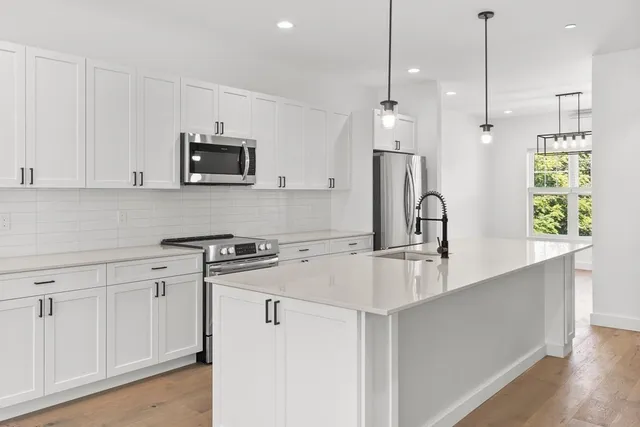 a kitchen with stainless steel appliances granite countertop a sink a stove a refrigerator a center island with wooden floor and cabinets