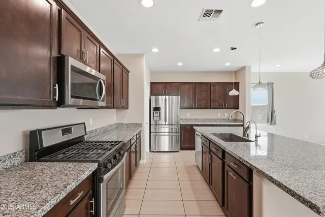 a kitchen with stainless steel appliances granite countertop a sink stove and refrigerator