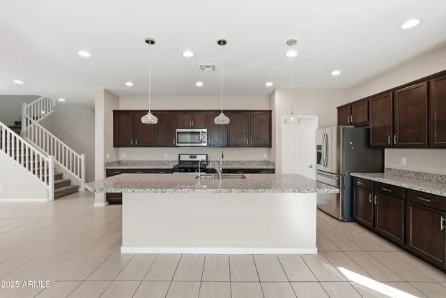 a large white kitchen with a large counter top stainless steel appliances and cabinets